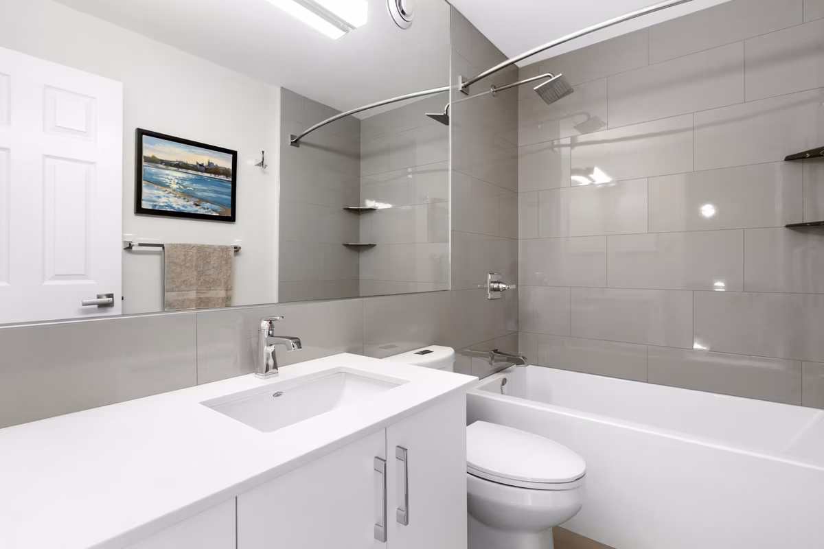 Minimalist white bathroom with grey tile accents, floating vanity, and coastal artwork