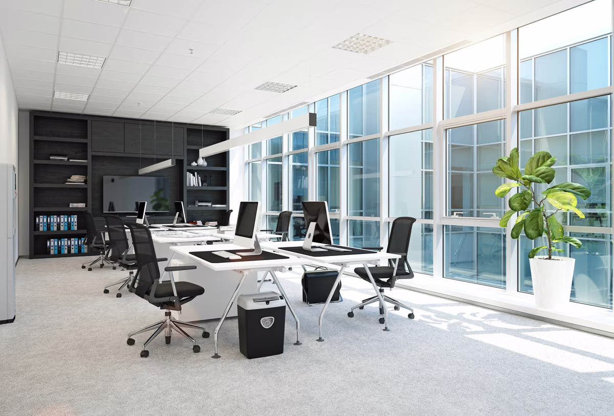 Bright modern office with white desks, ergonomic chairs, and large windows
