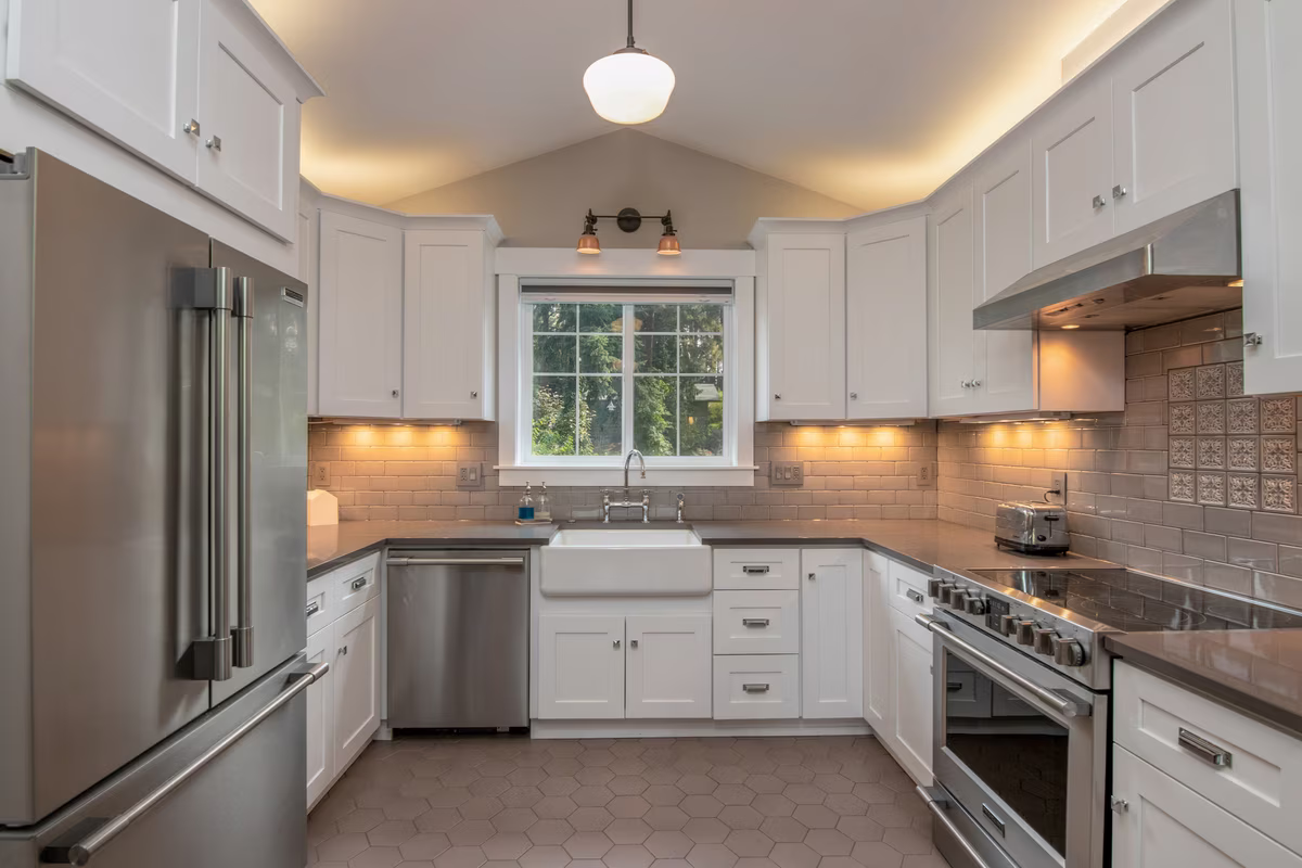 Modern U-shaped white kitchen with deep basin sink and stainless steel appliances
