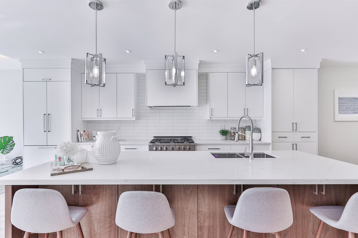 Modern white kitchen with chrome pendant lights and walnut-accented island