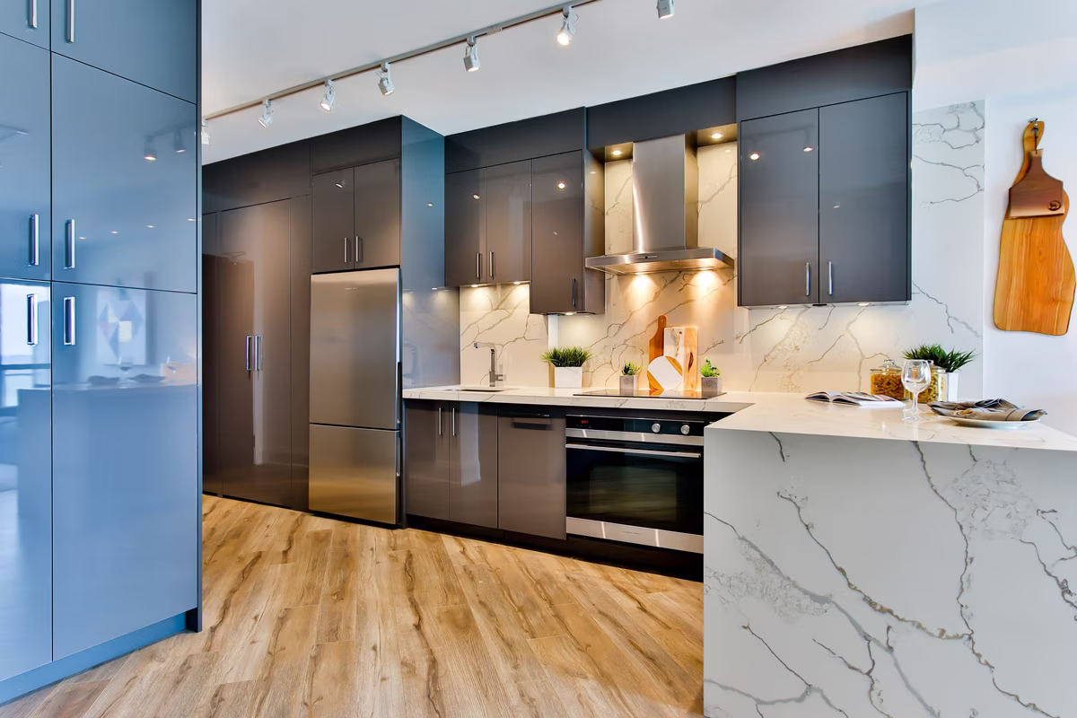 Modern two-tone kitchen with marble waterfall countertop and track lighting