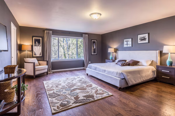Contemporary master bedroom with charcoal walls and nature views