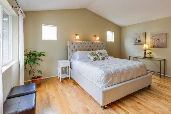 Transitional master bedroom with sage green walls and tufted headboard