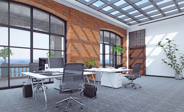 Loft-style office with exposed brick walls, large windows, and minimalist furniture
