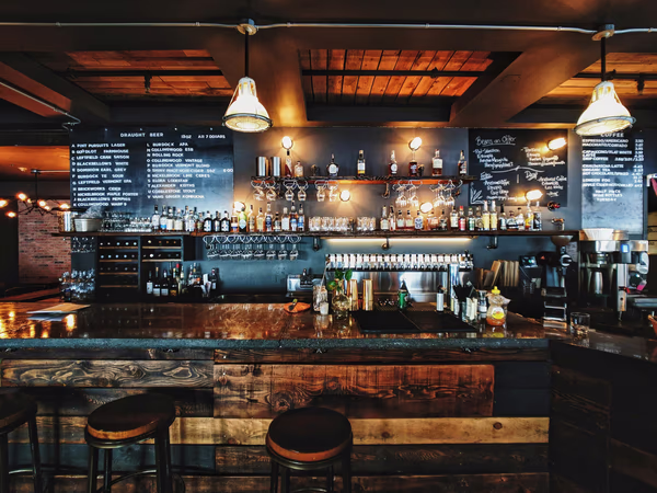 Rustic urban bar with wooden counter, high stools, and chalkboard menu