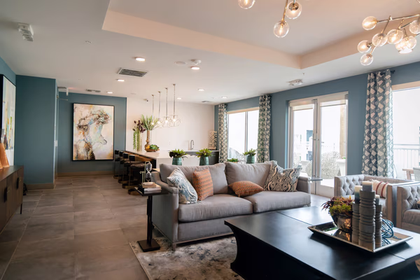 Modern living room with teal walls, grey sofa, and glass pendant lighting