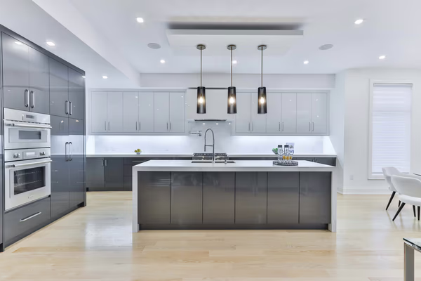 Luxury two-tone kitchen with cylindrical pendant lights and waterfall island