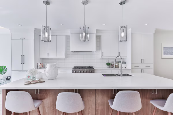 Modern white kitchen with chrome pendant lights and walnut-accented island