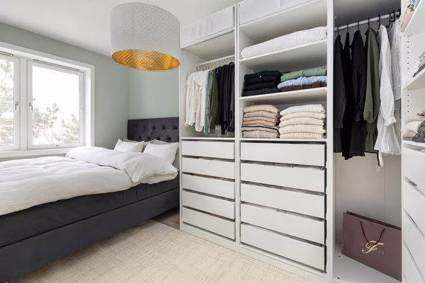 Modern bedroom with integrated white wardrobes and designer pendant lighting